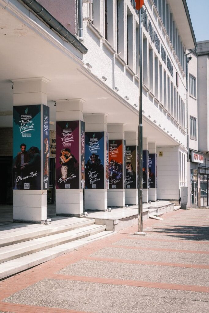 Theater exterior with vibrant festival posters on columns.